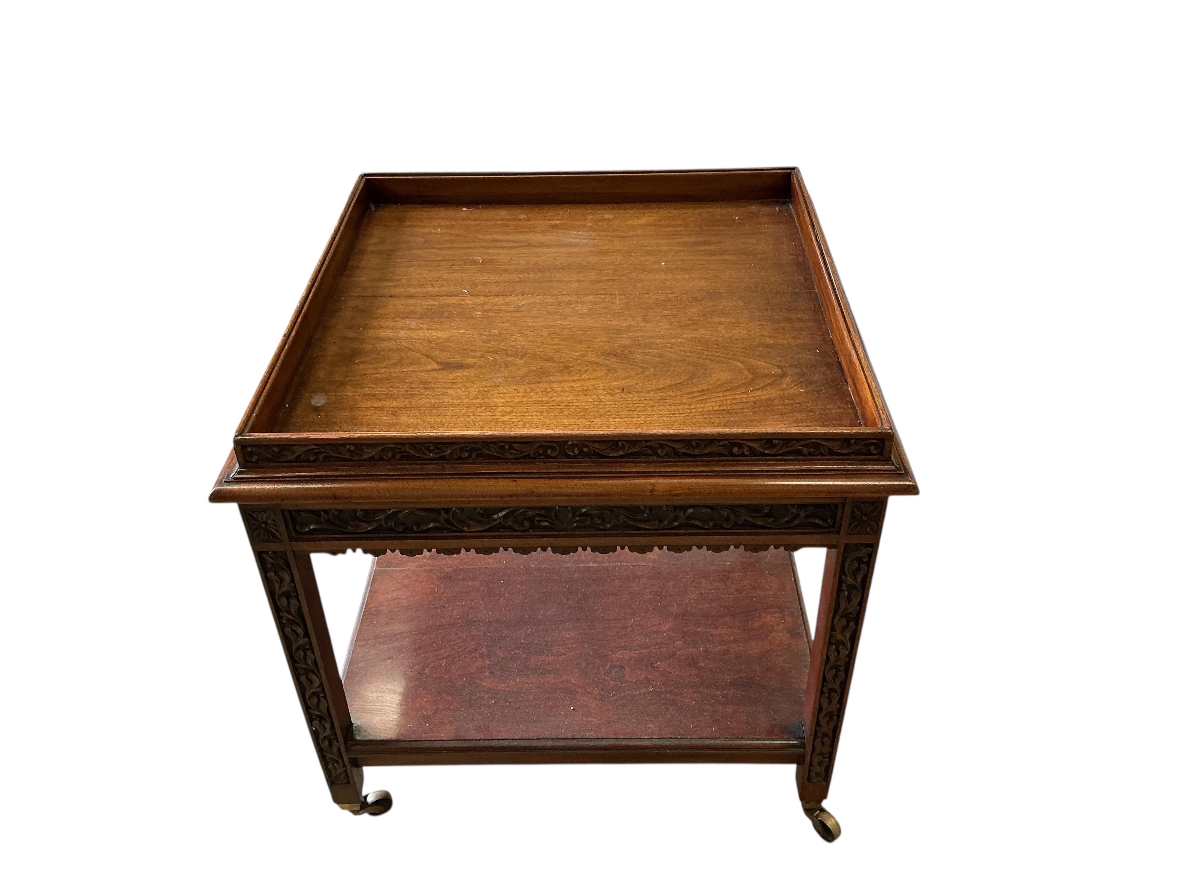 An early 20th century carved walnut square two tier occasional table, with brass caps and casters, 76cm, height 76cm